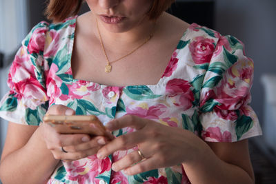 Midsection of woman using smart phone at home