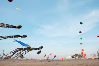Low angle view of balloons flying over beach against sky
