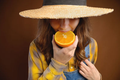 Studio portrait of an attractive caucasian young woman in a hat and denim overalls holds a cut