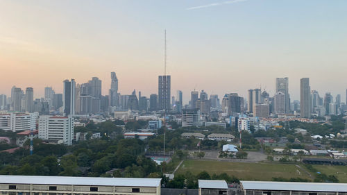 Modern buildings in city against sky during sunset