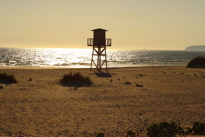 Silhouette lifeguard hut on beach against clear sky