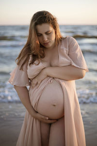 Young pregnant woman with a beautiful sea view on the background. happy and calm pregnant woman 