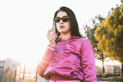 Young woman wearing sunglasses standing against sky