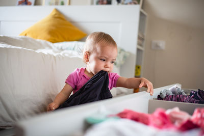 Baby playing with clothes in drawers, cleaning up the bedroom