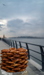 Close-up of bagels on table by sea against sky