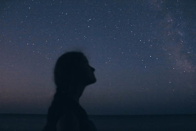 Silhouette man standing in sea against sky at night