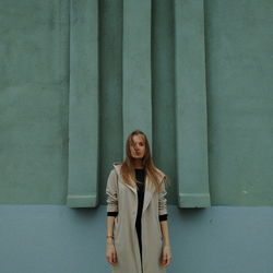 Portrait of young woman against wall