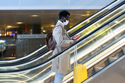 Side view of toy man wearing mask standing on escalator