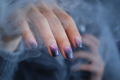 Midsection of woman with painted nails amidst smoke