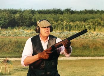 Senior man holding gun while standing on land