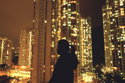Man and illuminated buildings in city at night