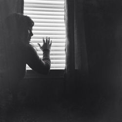Young woman standing against window at home