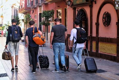 Rear view of people walking on sidewalk in city