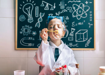 Boy wearing lap coat while sitting in classroom