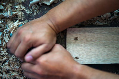 Wood shavings carpenter working with a metal spokeshave and a blurry background.