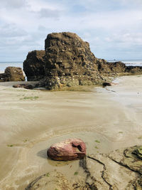 Rock formation on beach against sky