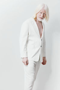 Portrait of young woman standing against white background