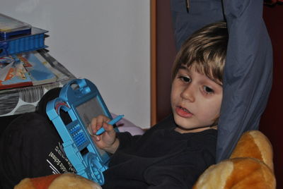 Cute boy holding toy while sitting at home