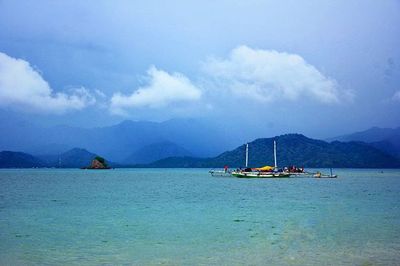 Boats in sea with mountains in background