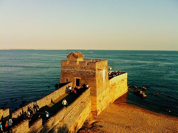 People by sea against clear sky