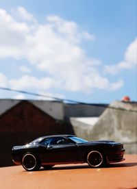 Close-up of vintage car on road against cloudy sky