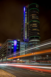 Light trails on road against buildings at night