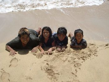 High angle view of wet children lying on shore