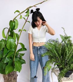 Young woman standing against plants