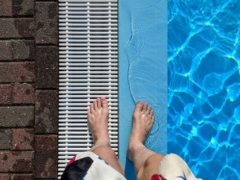 Low section of man standing by swimming pool