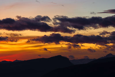 Scenic view of silhouette mountains against orange sky