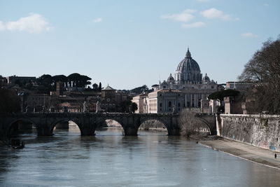 Arch bridge over river against buildings in city