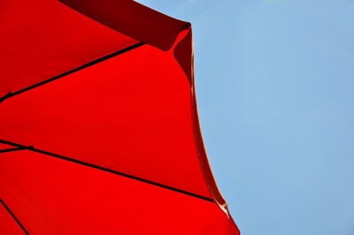 Low angle view of red umbrella against blue sky