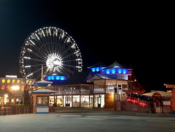 Illuminated ferris wheel against clear sky at night