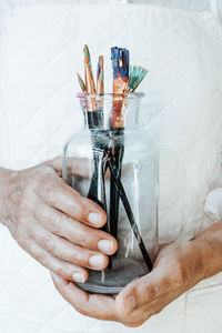 Cropped hand of woman holding container on table