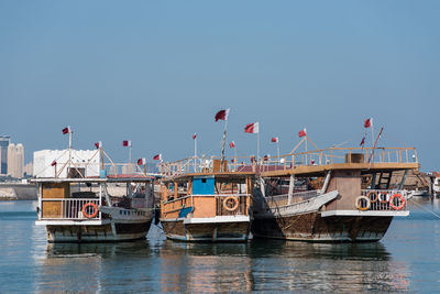 Boats moored at harbor against clear sky, doha, qatar 