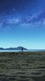 Man standing on beach against blue sky