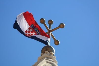 Low angle view of flag against clear blue sky