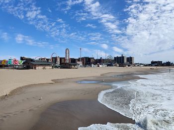 Scenic view of beach by buildings against sky