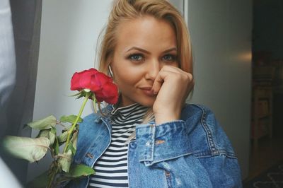 Portrait of beautiful young woman holding red rose