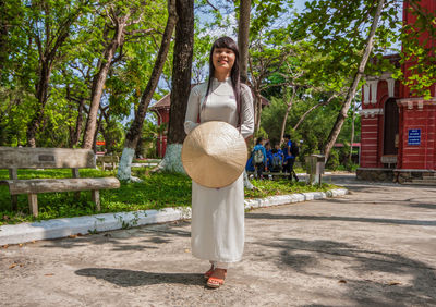 Portrait of woman standing by plants against trees