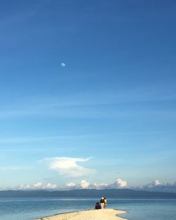 People sailing on sea against blue sky