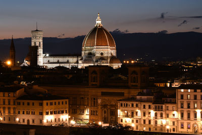 Illuminated buildings in city against sky