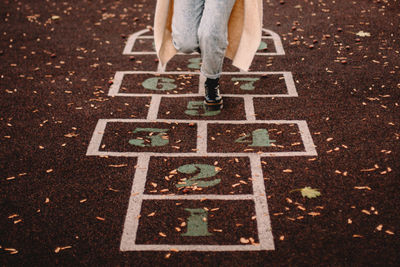 Cropped image of teenage girl playing hopscotch in park during autumn