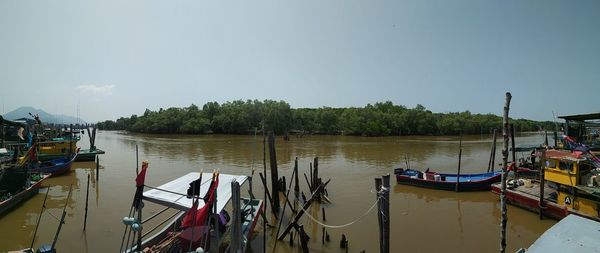 Boats moored at harbor against sky