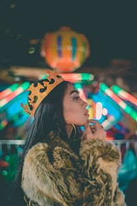 Portrait of woman looking at illuminated camera at night