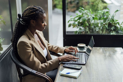 Businesswoman working on laptop at table in cafeteria