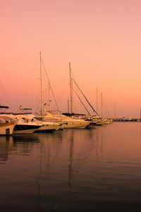 Boats moored on sea against clear sky during sunset