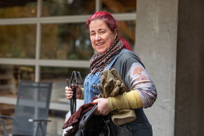 A red head female raku artist with tongs, gloves and protective gear