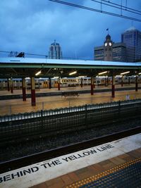 Train at railroad station in city against sky