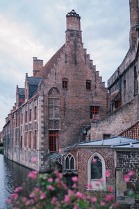 View of old building by canal against sky
